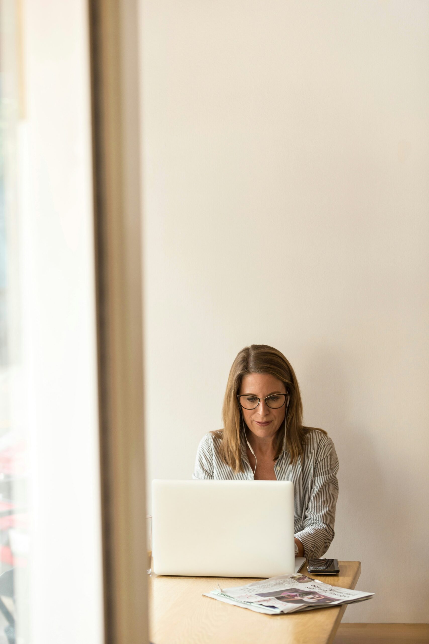 A woman can be seen working on a laptop with headphones on - Nurture Machines A woman can be seen working on a laptop with headphones on