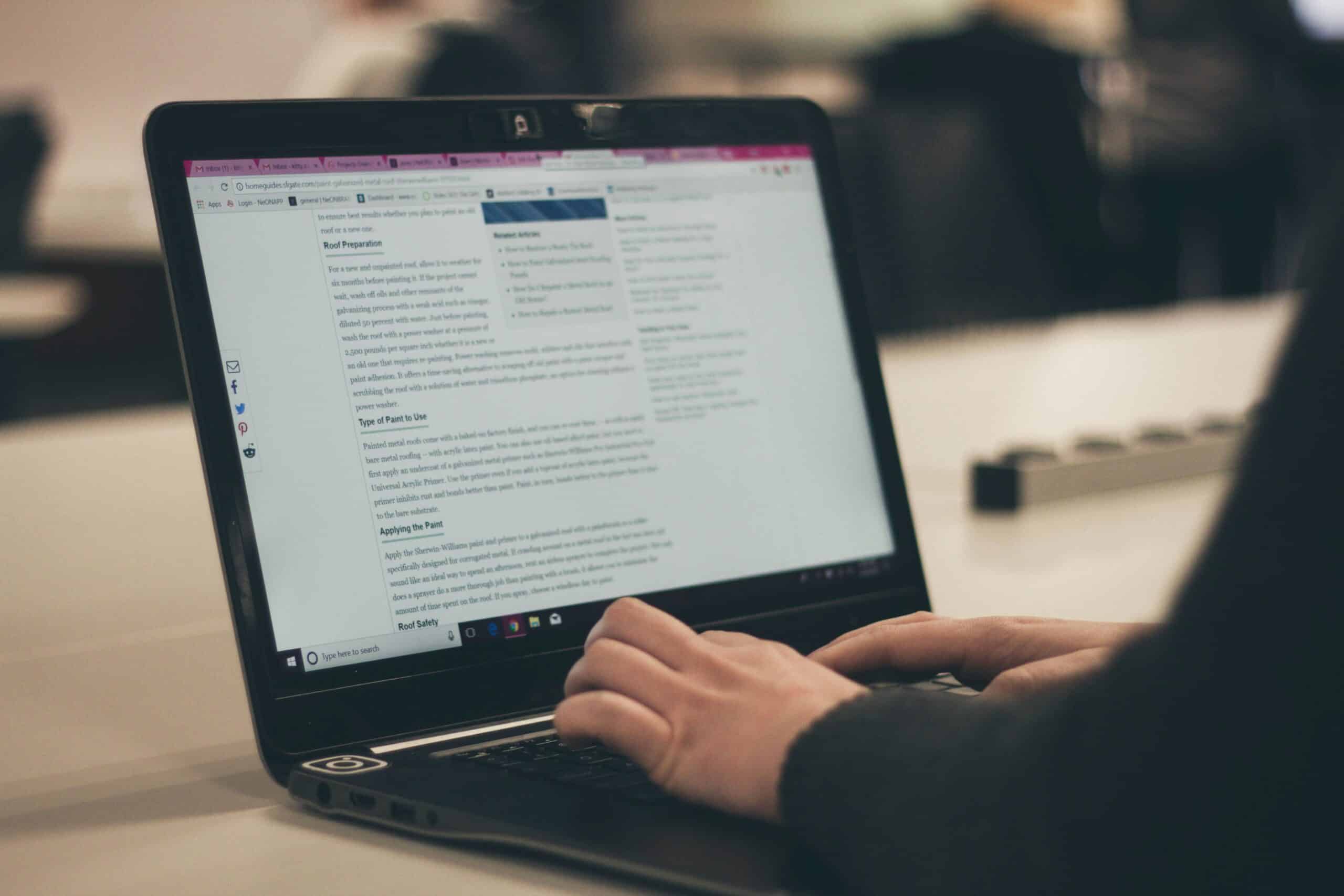 A person types on a laptop screen displaying a text-heavy webpage, emphasizing the importance of structuring content with clear headings and sections for easy readability and scanning.