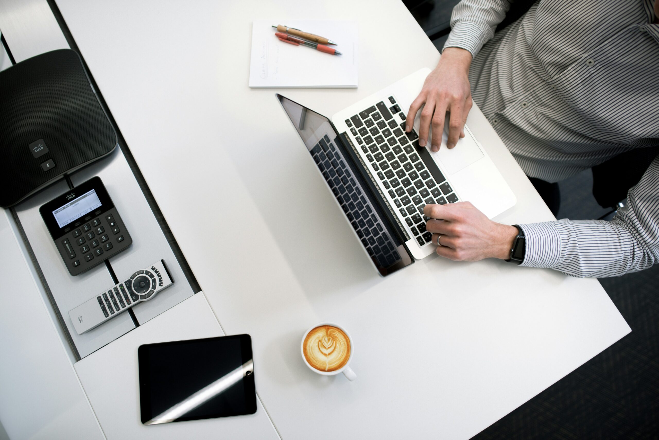 Person working on laptop with coffee and office tools - Nurture Machines Person working on laptop with coffee and office tools