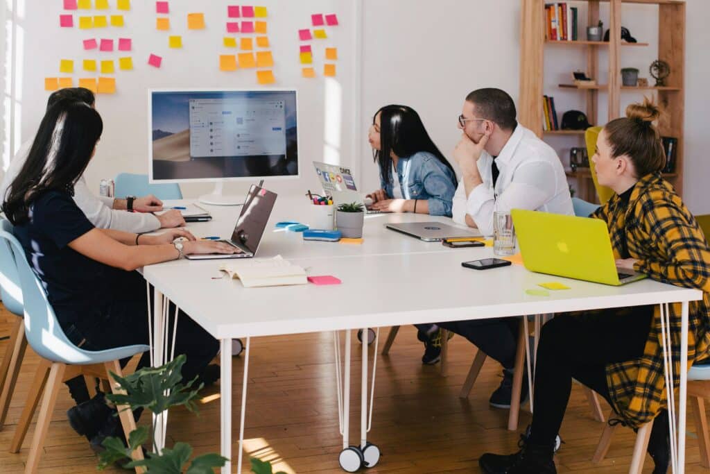 A marketing team collaborates around a screen, analyzing how MQLs and SQLs progress through the sales funnel to support lead conversion.