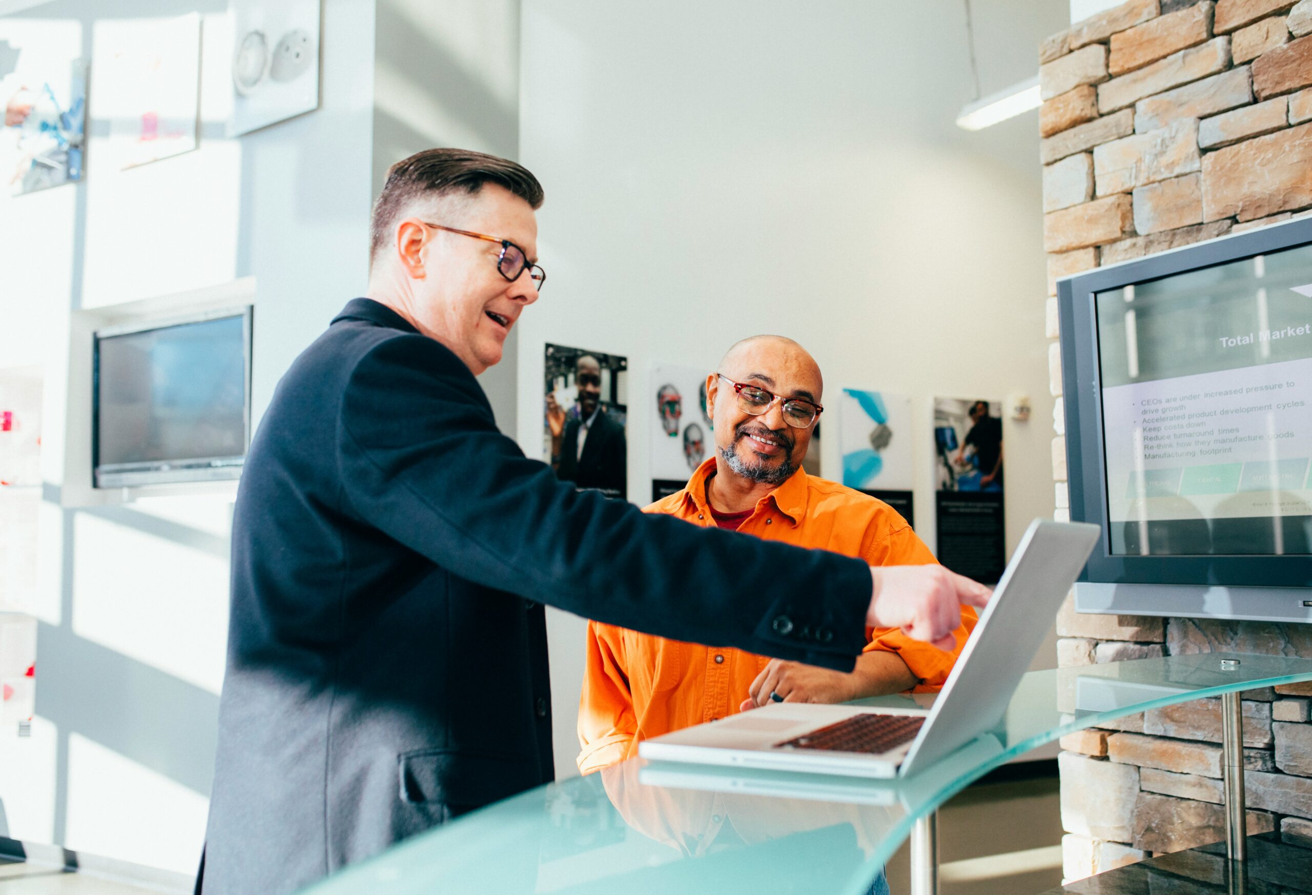 Two professionals review a laptop screen together in a modern office, representing smart sales funnel tactics used to convert leads into cost-effective sales.