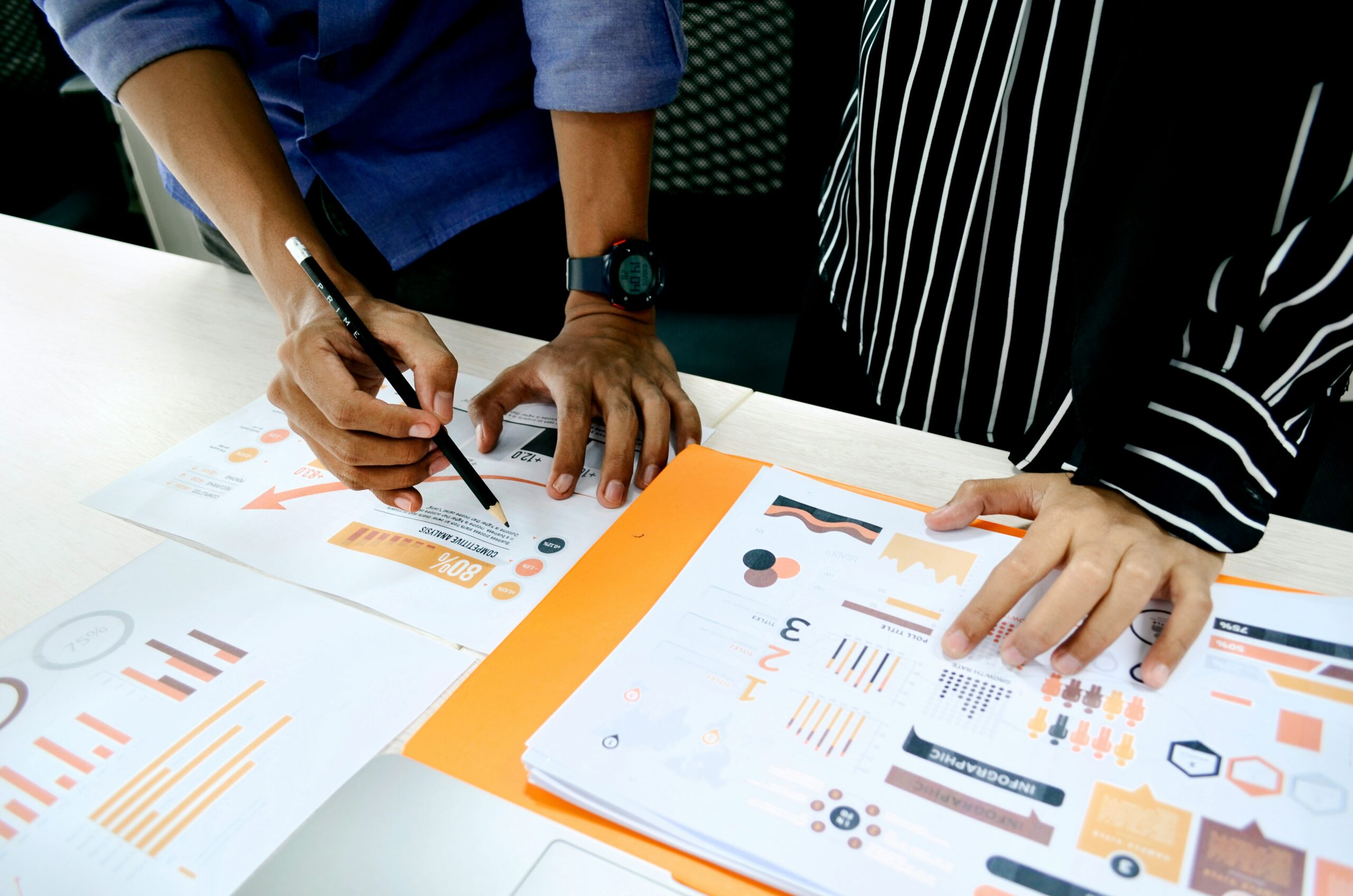 Two individuals analyzing printed marketing charts, representing the distinction between automated lead nurturing and traditional engagement techniques.