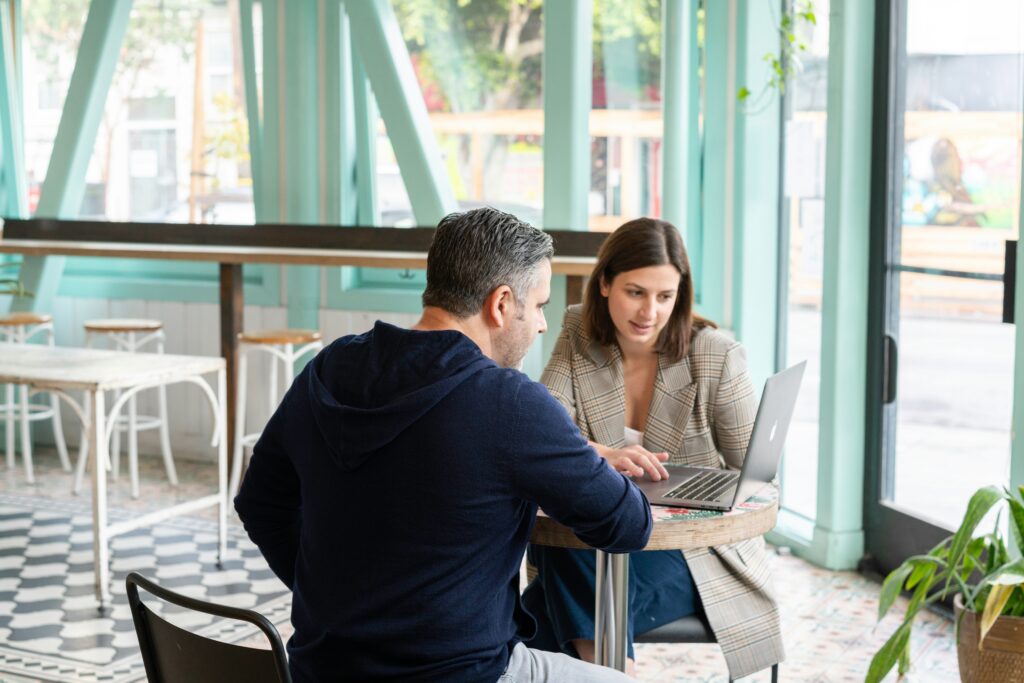 Two professionals discussing lead nurturing strategies on a laptop, highlighting the benefits of automation for customer relationship growth.