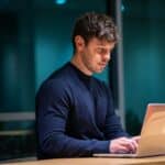 Focused professional reviewing laptop data, analyzing top-of-funnel performance for ongoing marketing improvement.
