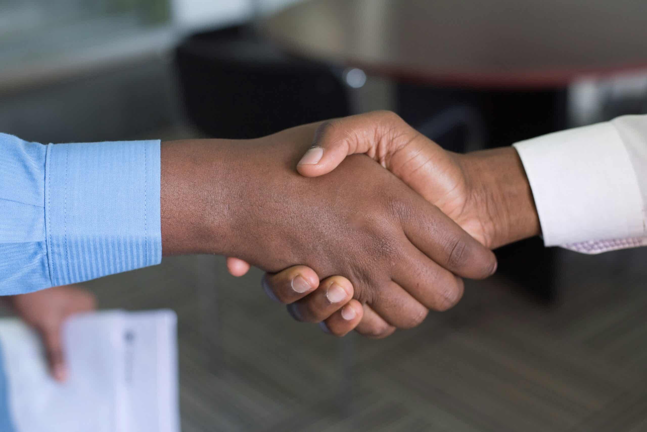 Two people shaking hands in a professional setting, symbolizing trust and credibility—key elements for enhancing user experience and boosting conversion outcomes.