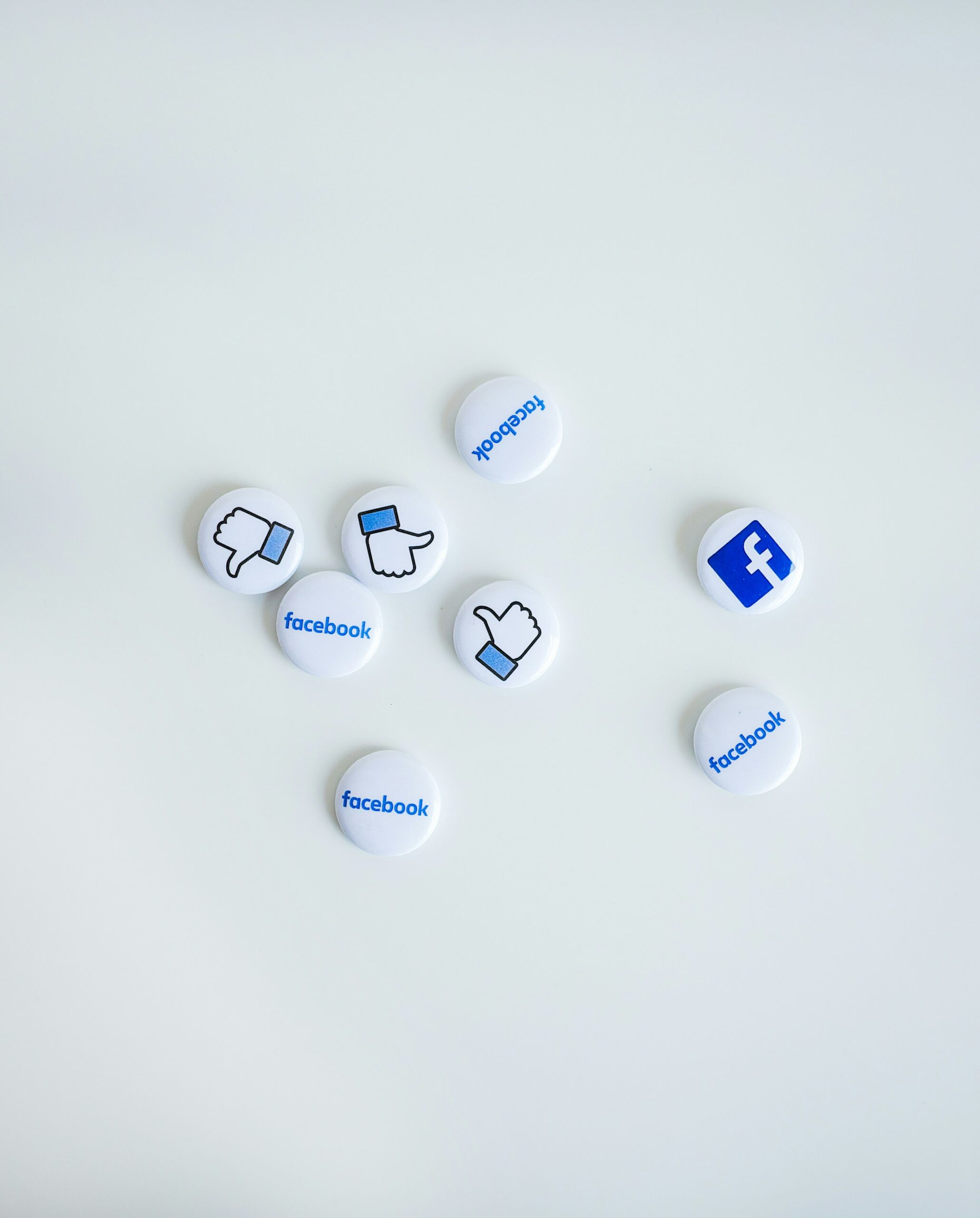 Flat-lay of Facebook-themed pins featuring thumbs up, thumbs down, and logo icons, symbolizing the consideration of alternative ad platforms to optimize acquisition spending. - Nurture Machines Flat-lay of Facebook-themed pins featuring thumbs up, thumbs down, and logo icons, symbolizing the consideration of alternative ad platforms to optimize acquisition spending.