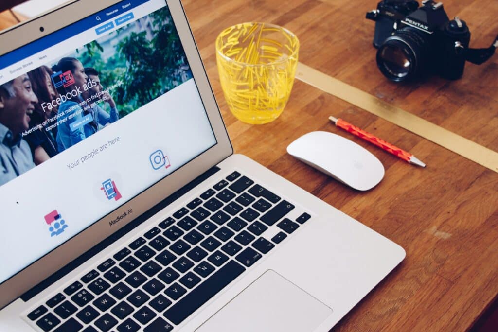 A laptop displaying a Facebook Ads page on a wooden desk, symbolizing the role of targeted social media advertising in boosting customer acquisition.