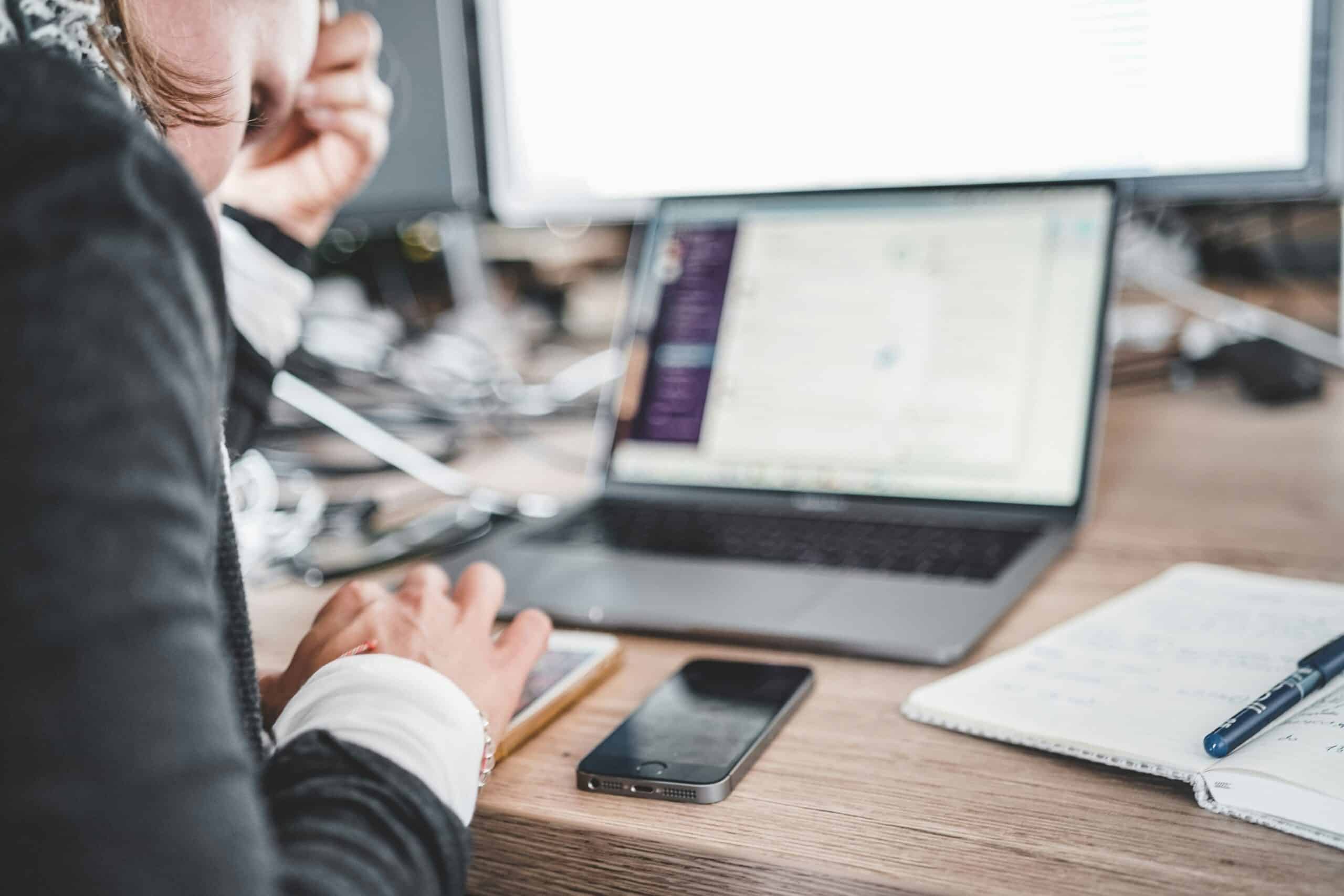 A person uses a laptop and smartphone with handwritten notes nearby, planning personalized upselling strategies based on digital customer behavior. - Nurture Machines A person uses a laptop and smartphone with handwritten notes nearby, planning personalized upselling strategies based on digital customer behavior.