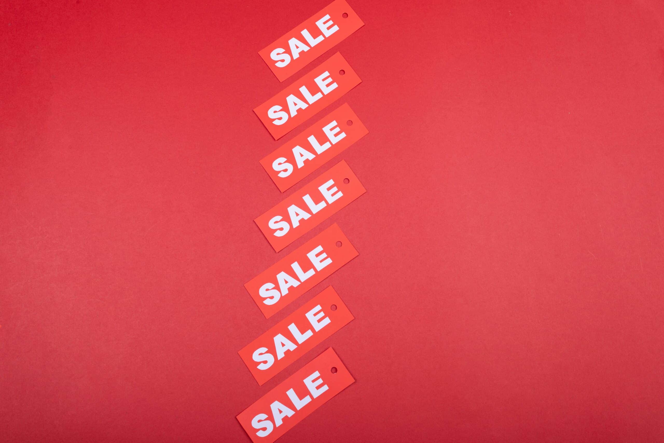 Red sale tags arranged diagonally on a red background, symbolizing how discounts and promotions can encourage customers to complete purchases and reduce cart abandonment. - Nurture Machines Red sale tags arranged diagonally on a red background, symbolizing how discounts and promotions can encourage customers to complete purchases and reduce cart abandonment.