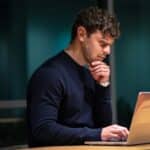 A focused professional researching on a laptop, exploring the most effective customer acquisition channels for business growth.