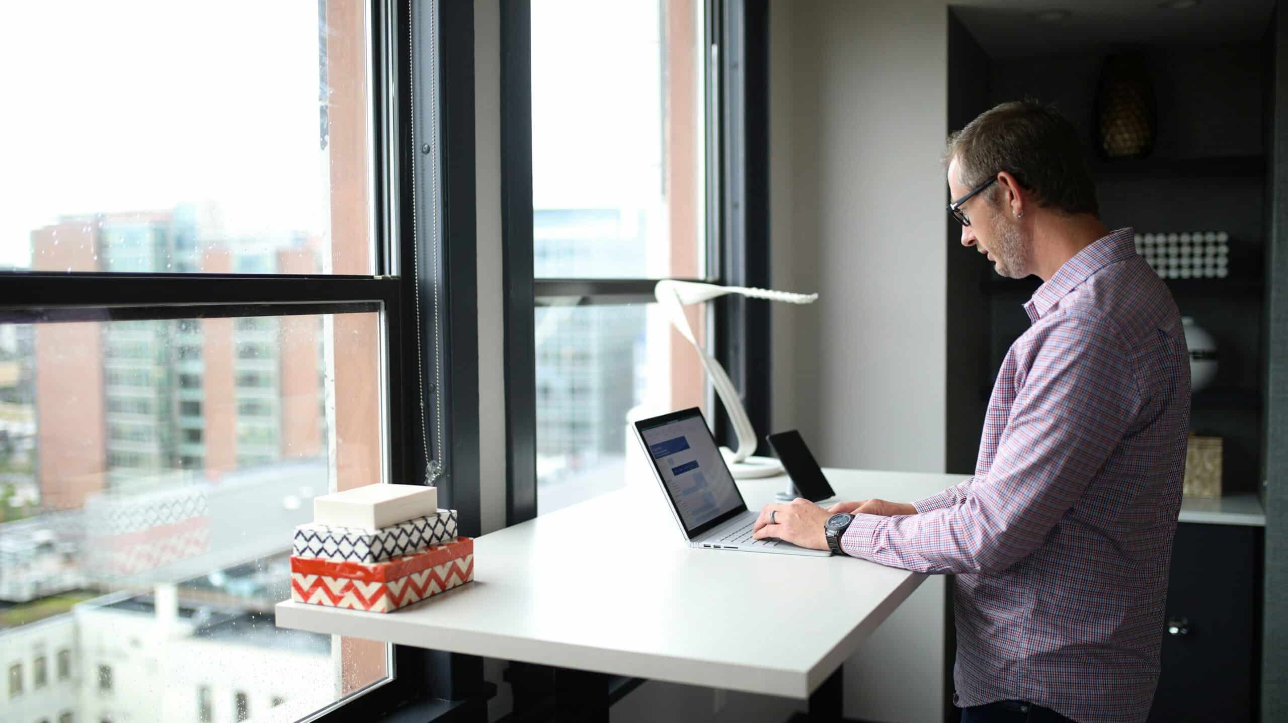 A man working on a laptop near a window, using personalized marketing insights to tailor strategies that enhance customer lifetime value.