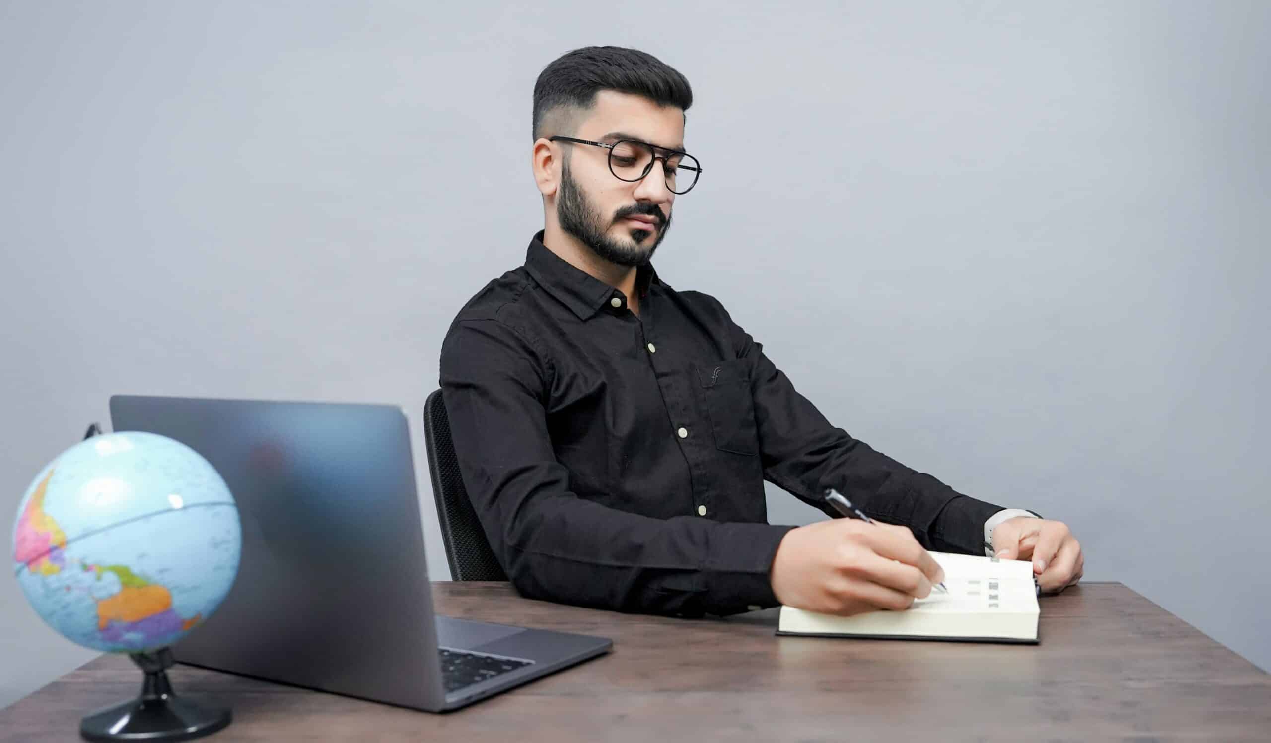 A professional reviews notes beside a laptop and globe, symbolizing how industry-specific customer acquisition cost benchmarks guide strategic growth decisions across markets.