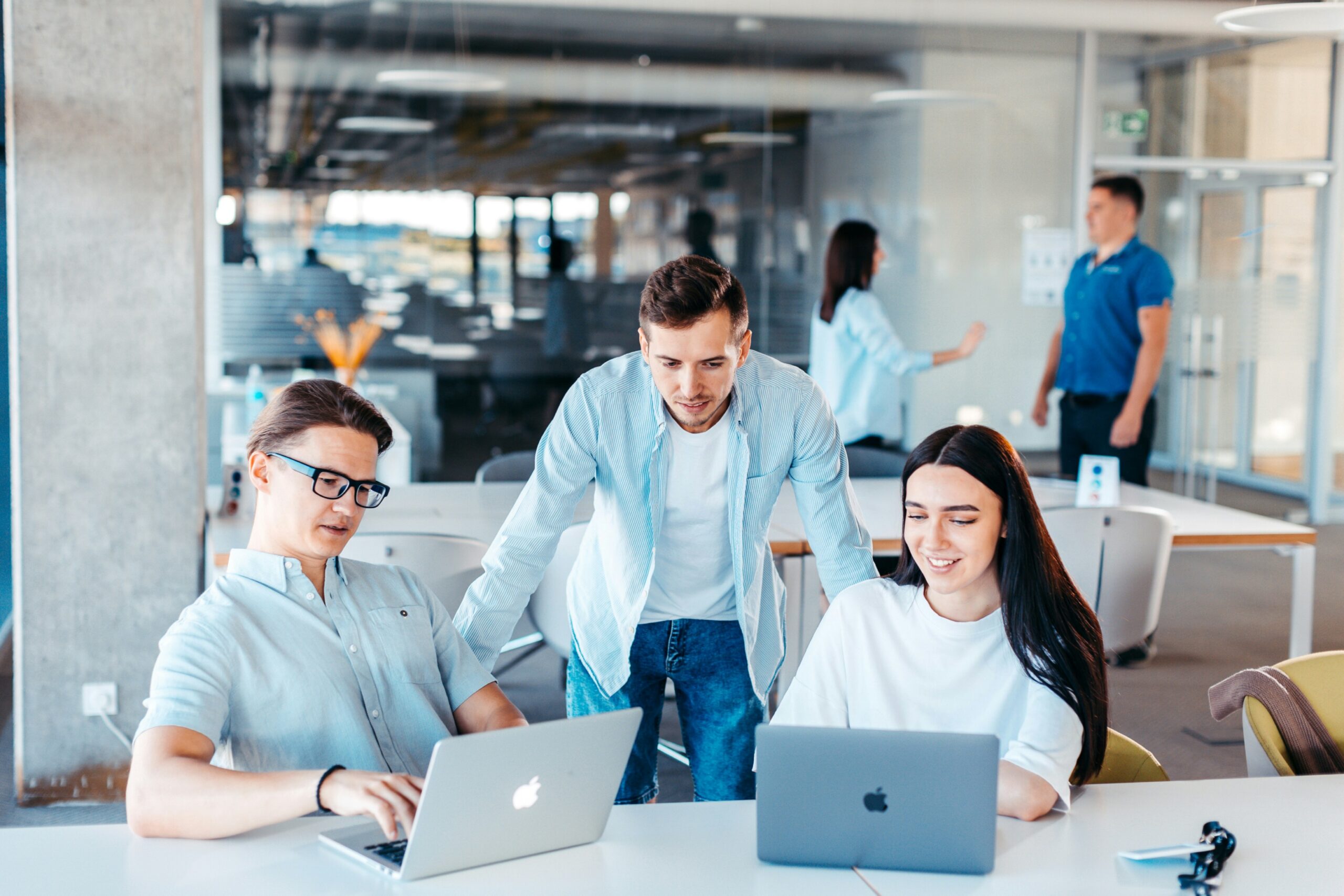 A group of professionals collaborates over laptops to analyze market trends and competitor data, uncovering key opportunities for acquisition improvements.