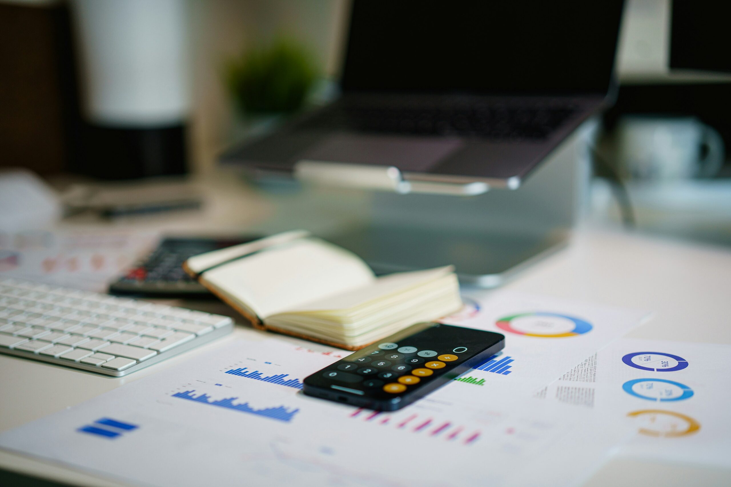 A workspace with charts, a calculator, and a notebook illustrates how data analytics and reporting help track performance metrics to optimize customer acquisition strategies.