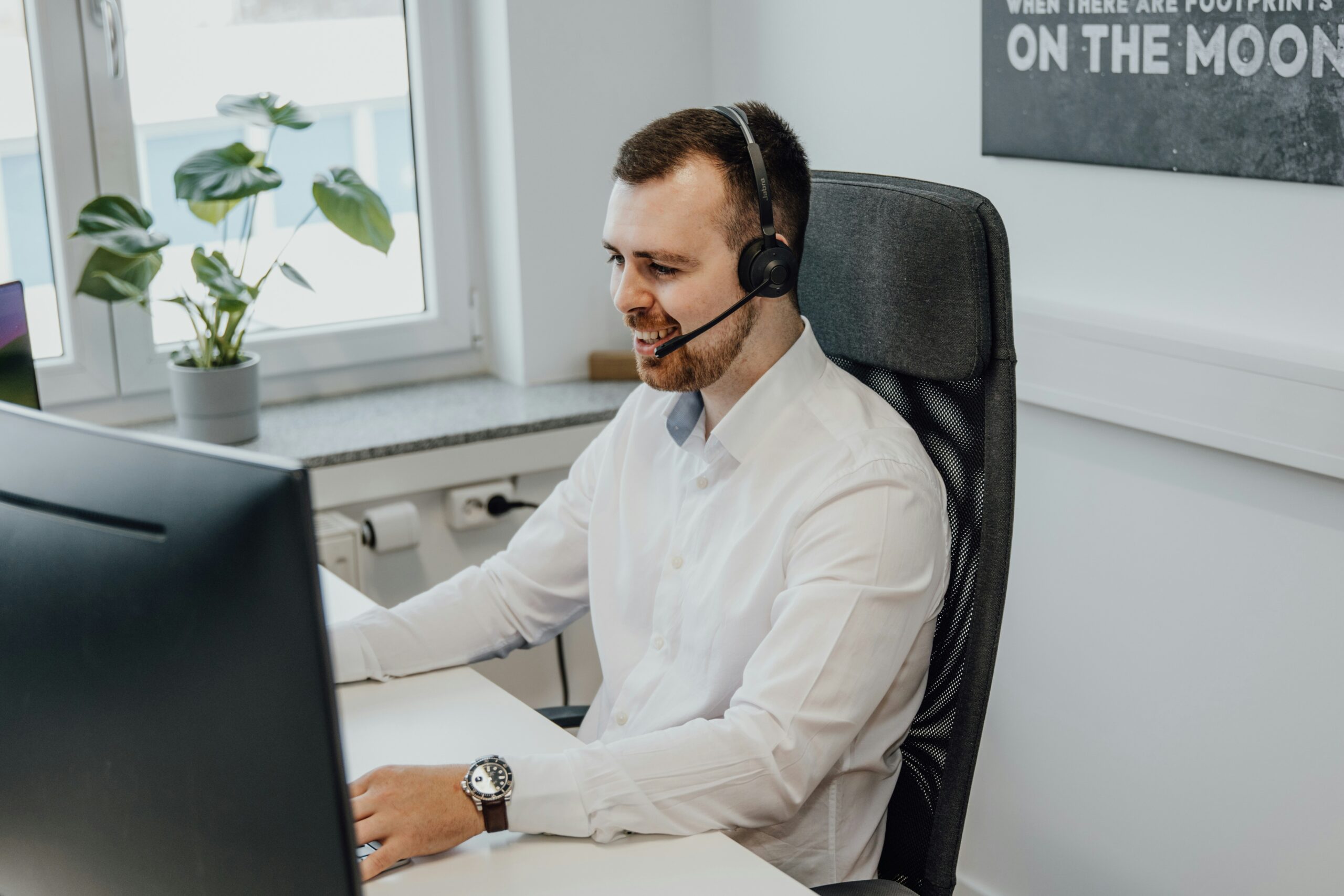 A smiling support agent wearing a headset engages with a client, highlighting how proactive customer support builds trust and improves acquisition by addressing needs before issues arise.
