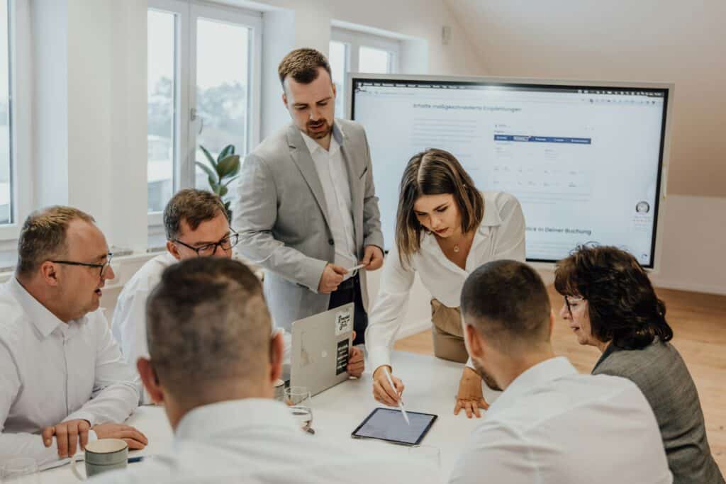 Team collaborating around a tablet, using customer feedback to refine marketing strategies and improve message clarity and relevance.