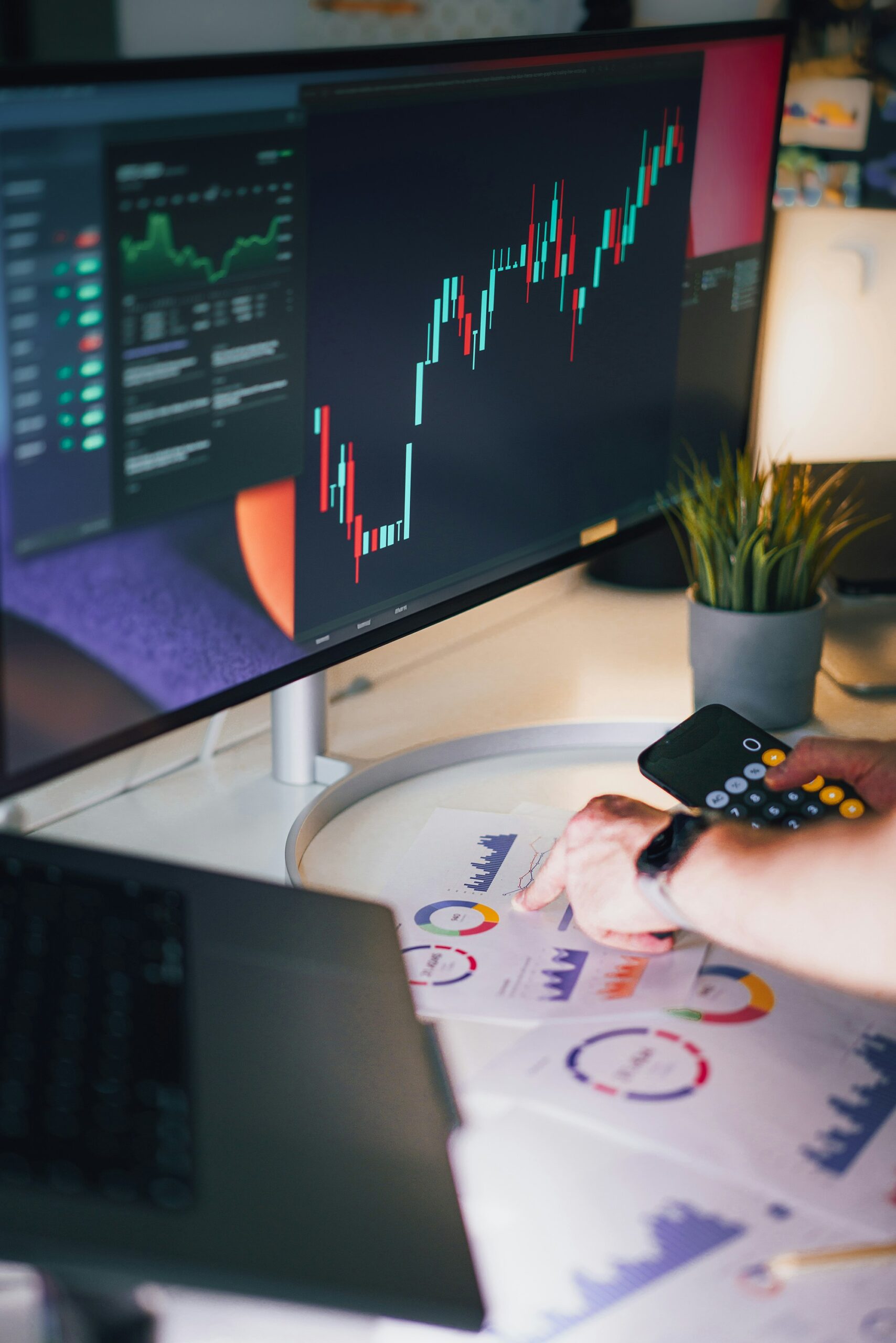 A person analyzes charts and performance graphs on a monitor and desk to evaluate the success of customer acquisition strategies using key metrics.