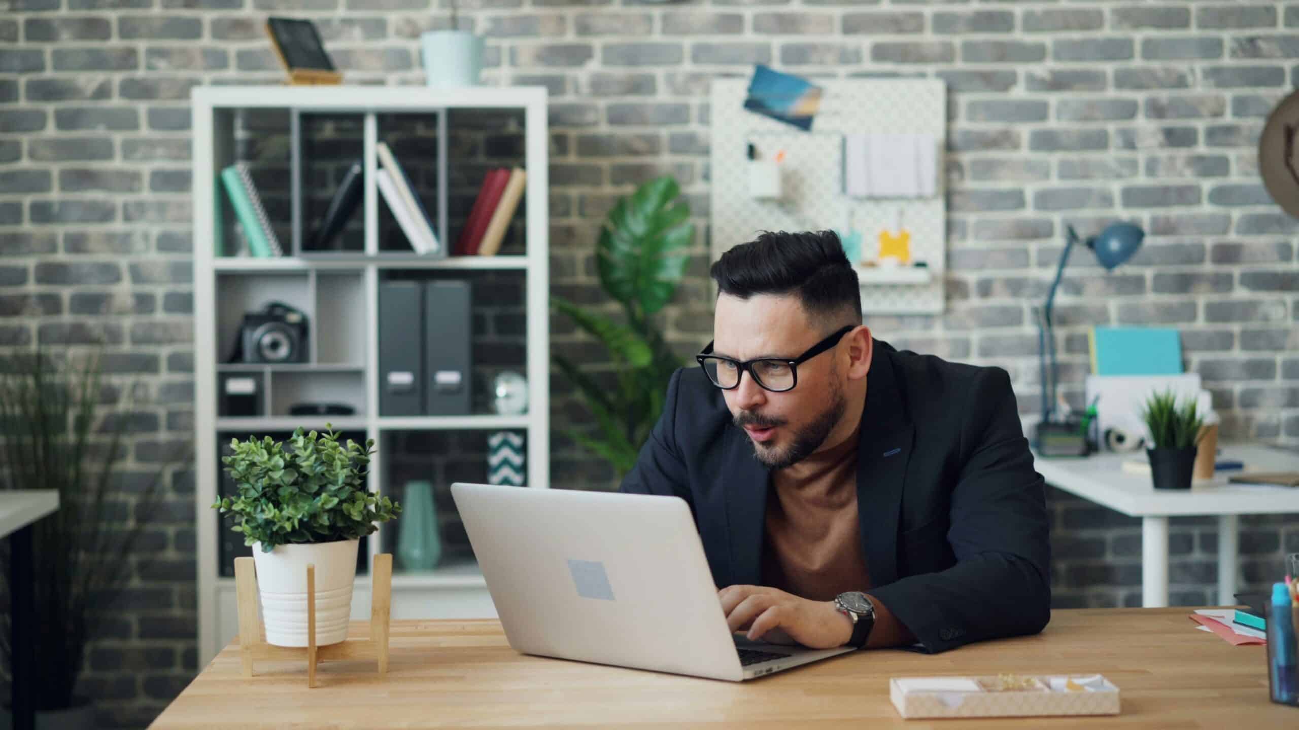A focused professional works on a laptop in a modern office, symbolizing efforts to research and understand the specific needs of a target audience.