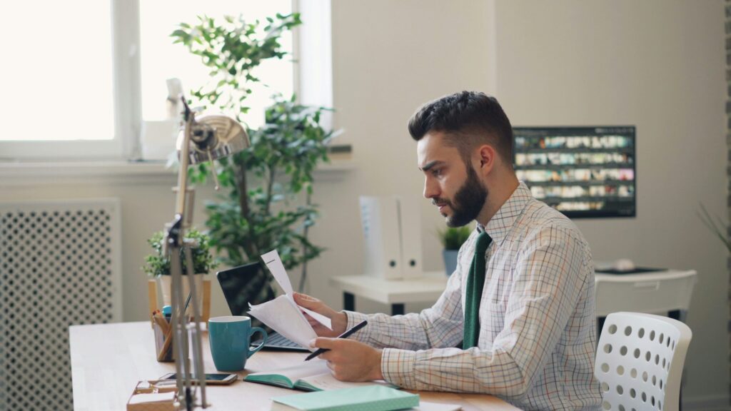 A marketing professional analyzes reports at a desk, identifying which marketing channels to optimize based on current market trends and campaign data.