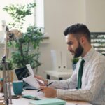 A marketing professional analyzes reports at a desk, identifying which marketing channels to optimize based on current market trends and campaign data.